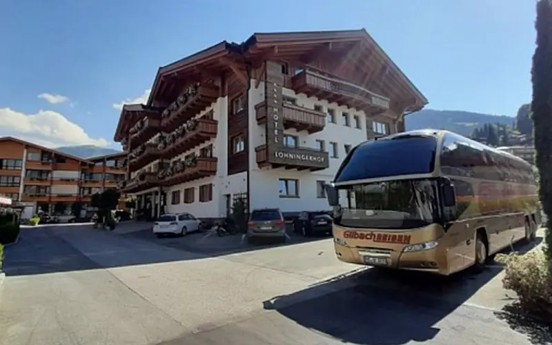 Bus von Gilbach Reisen vor einer historischen Hütte